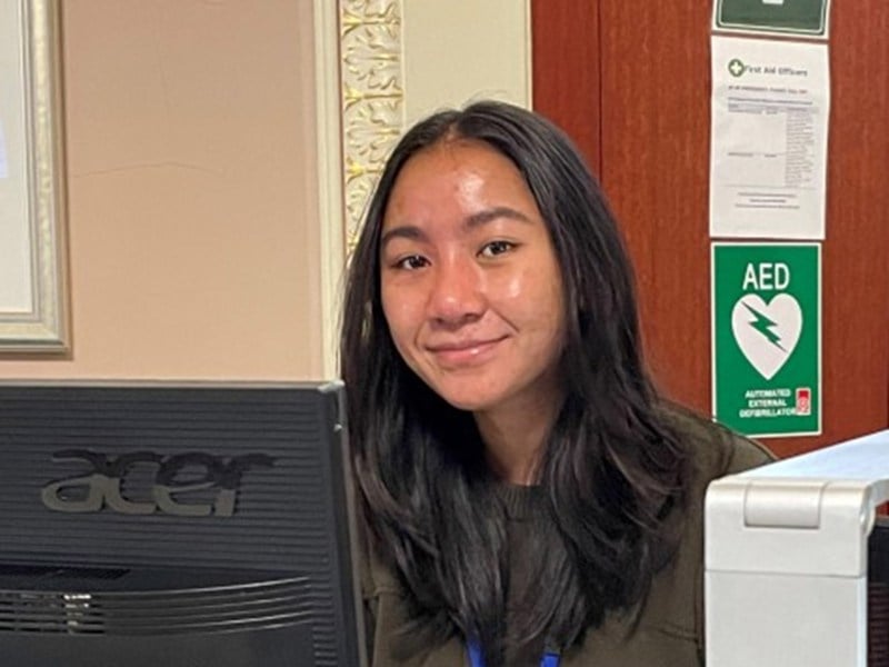 Sitting program student Wani assisting with visitor registration in the Vestibule